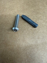 A silver metal threaded screw bolt and a dark gray hexagonal plastic or rubber insert placed on a brown textured cardboard background.