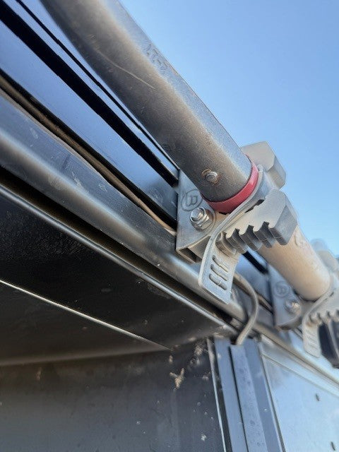 Close-up of a metal bracket attached to a vehicle's exhaust system with a clear sky background.